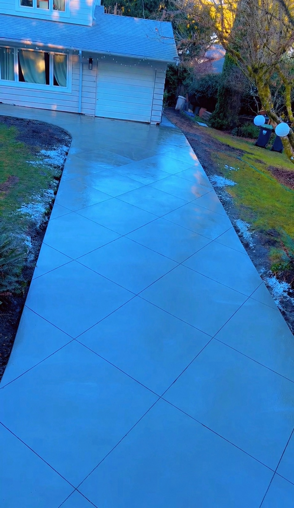 Finished driveway photographed at dusk with the house lit behind it